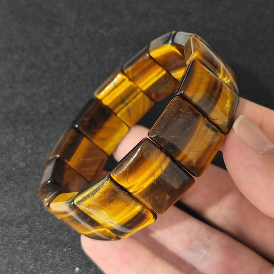 premium natural yellow tigers eye plate cuff bracelet held in hand highlighting vibrant golden sheen