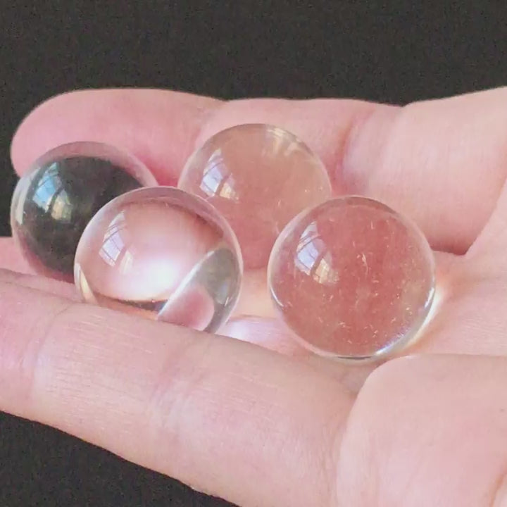 Natural clear quartz sphere (~2cm), highly transparent with glassy luster, resting on a small resin base; premium crystal desk decor for mindful spaces