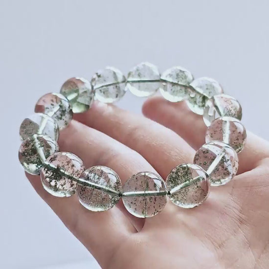 Green phantom quartz bracelet gently curved—highlighting elasticity, smooth polish, and dense green phantom patterns