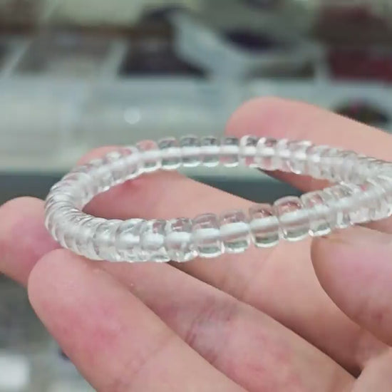 Transparent natural clear quartz disc bead stretch bracelet displayed on white background, smooth polished surface, no clasp