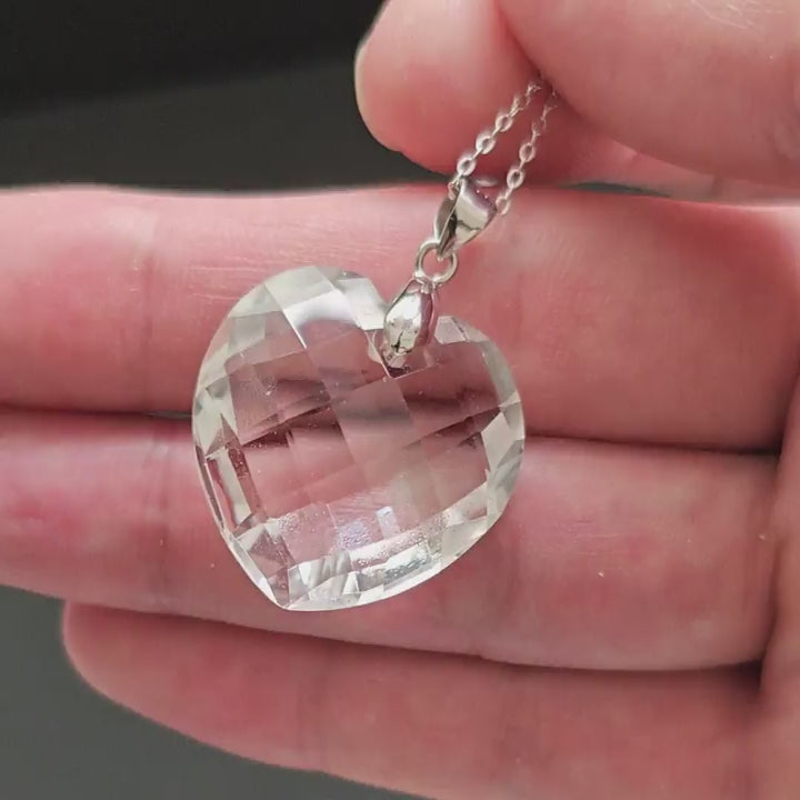 Natural clear quartz heart-shaped pendant with S925 silver chain, displayed flat on black background, showcasing geometric facets and transparent clarity