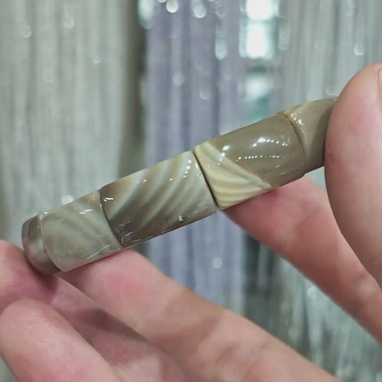 Gentle touch on picture jasper bead—highlighting the subtle luster and natural variation in earth-tone patterns