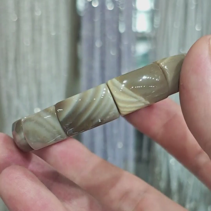 Gentle touch on picture jasper bead—highlighting the subtle luster and natural variation in earth-tone patterns