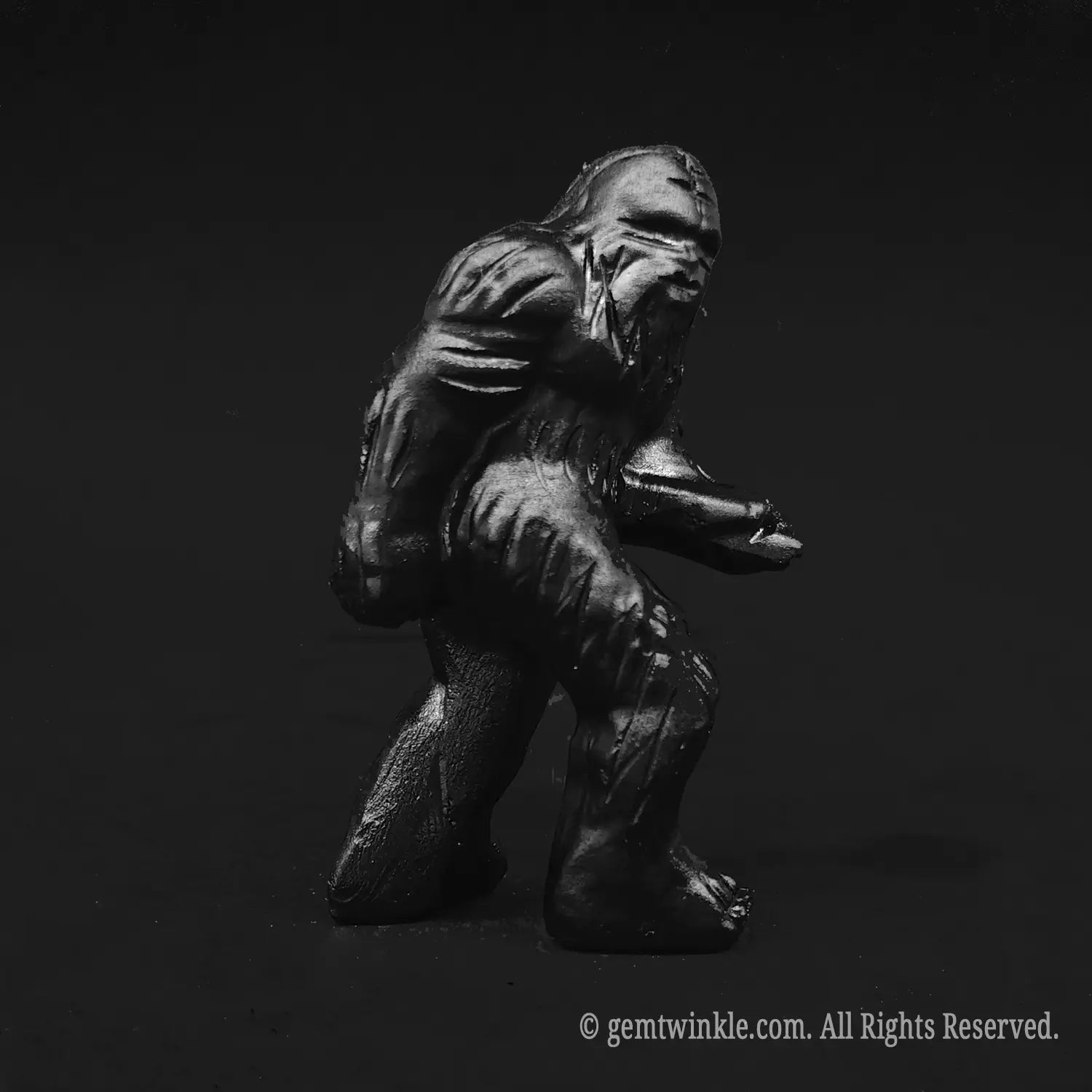 Full profile view of a protective black obsidian bigfoot figurine showcasing glossy volcanic dark surface and hand carved details