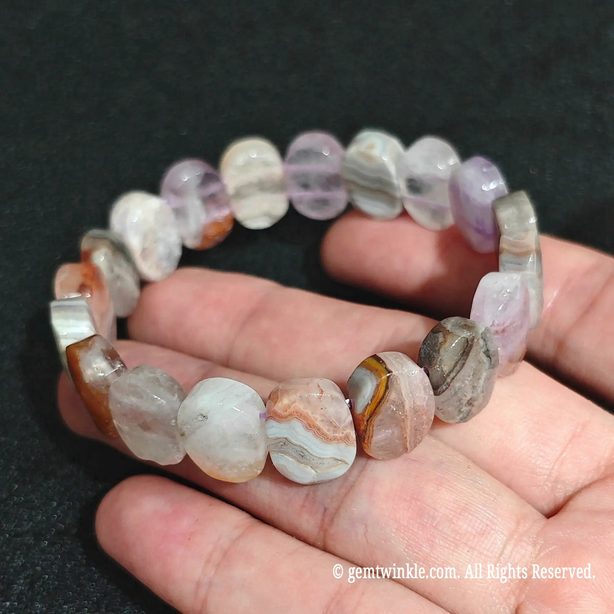 Angled view of an organic amethyst chalcedony bracelet highlighting its polished pebble shape
