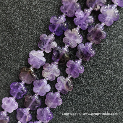 Angled view of natural purple amethyst floral carved gemstone strands laid together