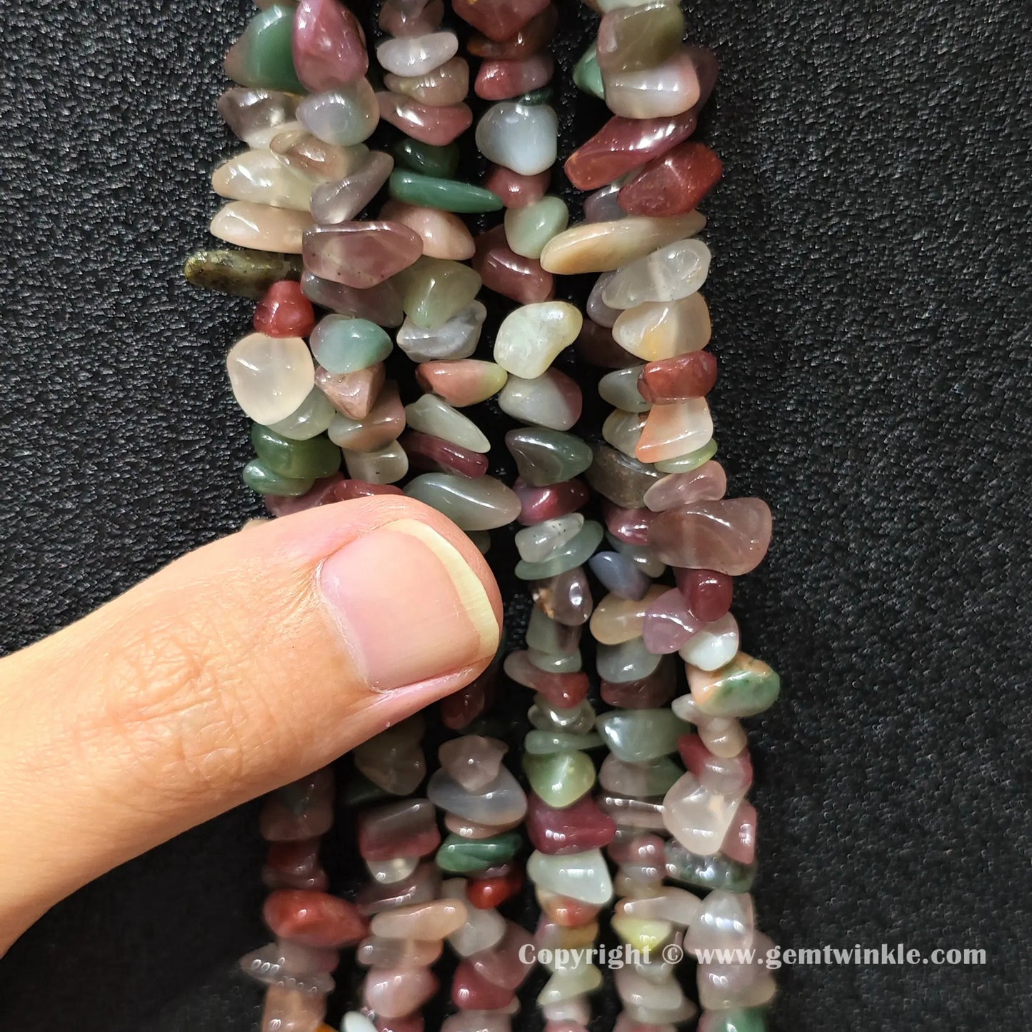Natural purple green agate chip bead strand held over hand for size scale
