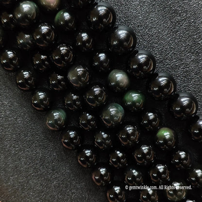 Natural rainbow obsidian crystal beads strands showing rich purple and green dual-color flash under direct light