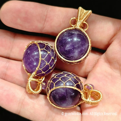 Group view of 20mm amethyst sphere pendants held in hand highlighting gold wire cage design for jewelry making
