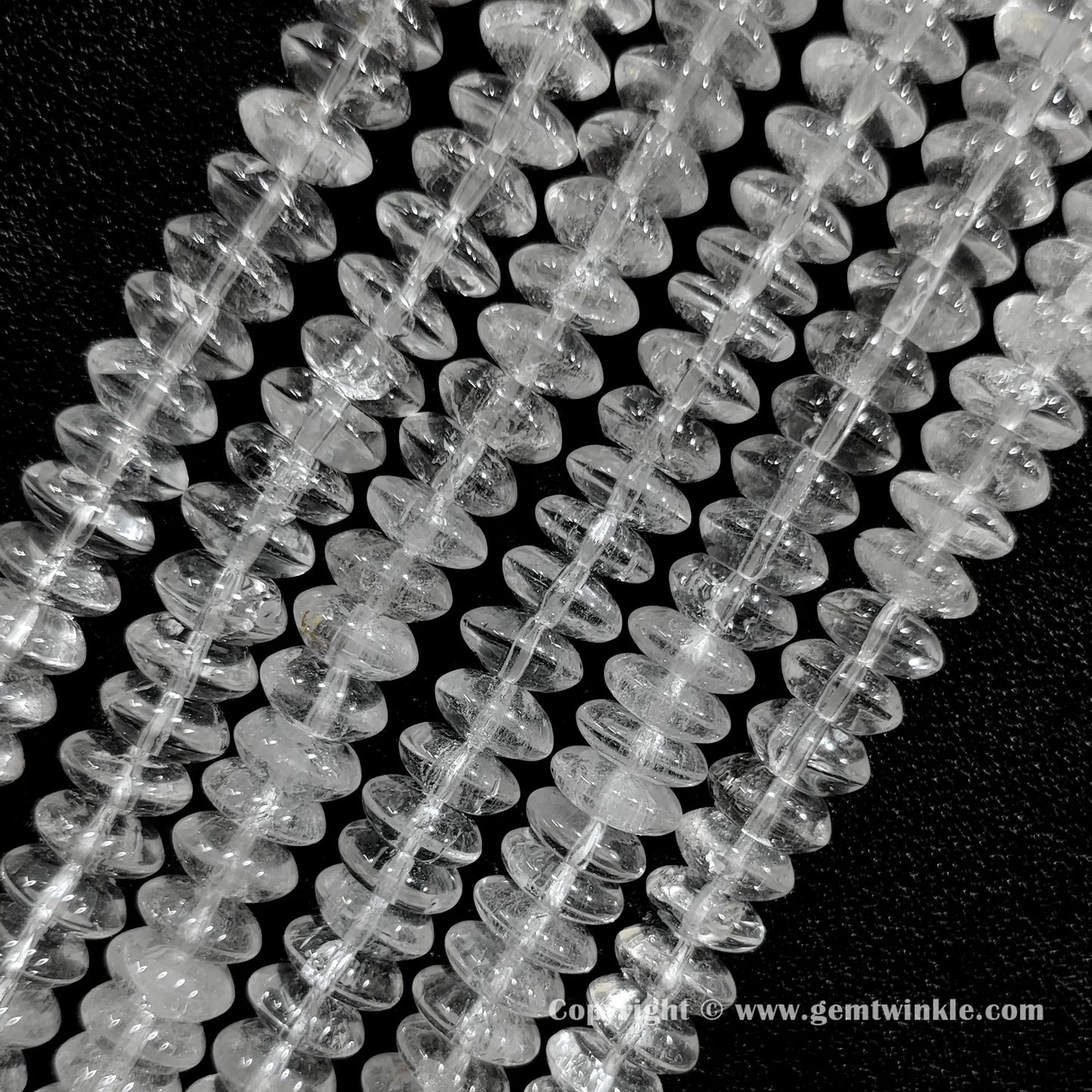 Angled view of clear quartz disc spacer gemstone strands displaying natural internal crack patterns