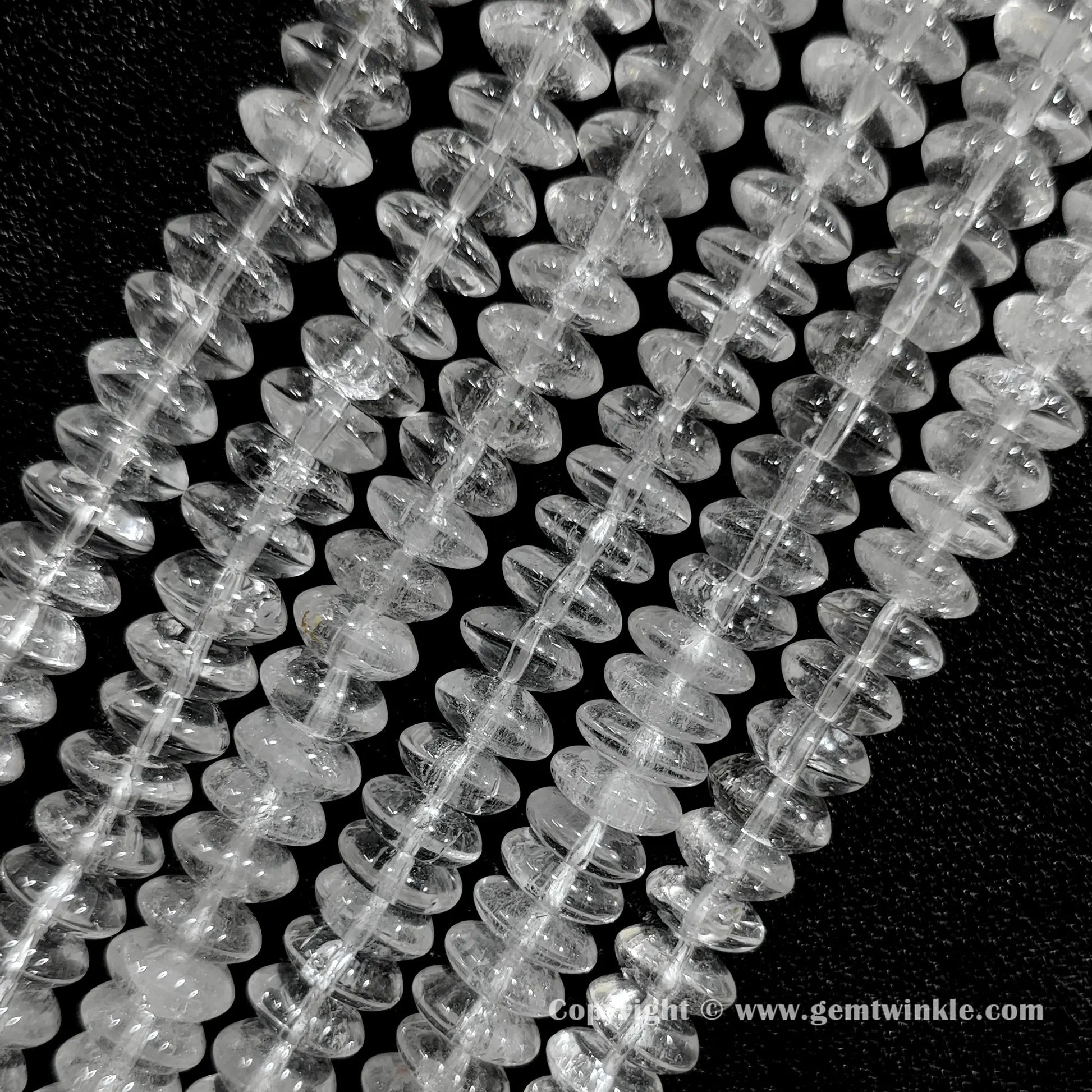 Angled view of clear quartz disc spacer gemstone strands displaying natural internal crack patterns