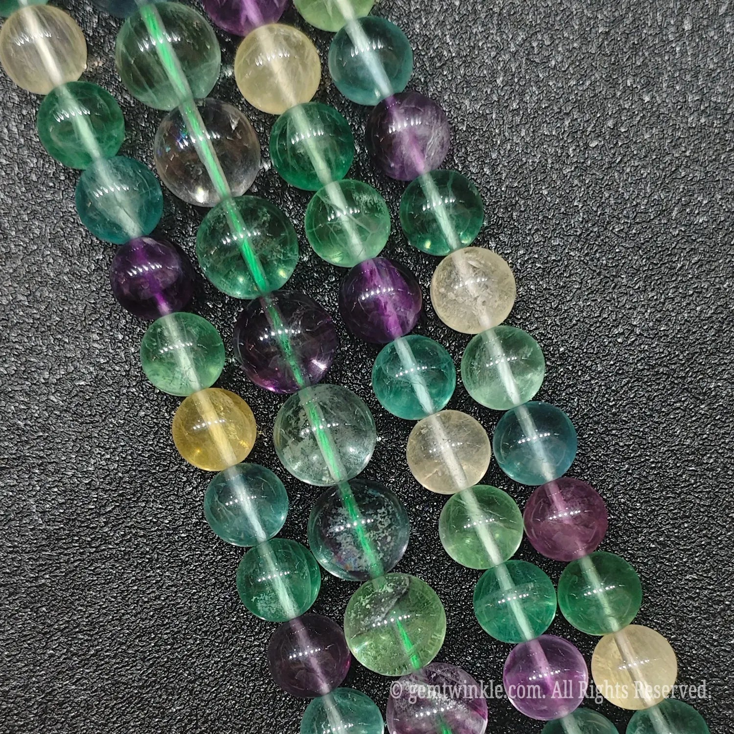 Close up view of natural rainbow fluorite crystal strands highlighting the rich variety of yellow green and purple translucent round beads