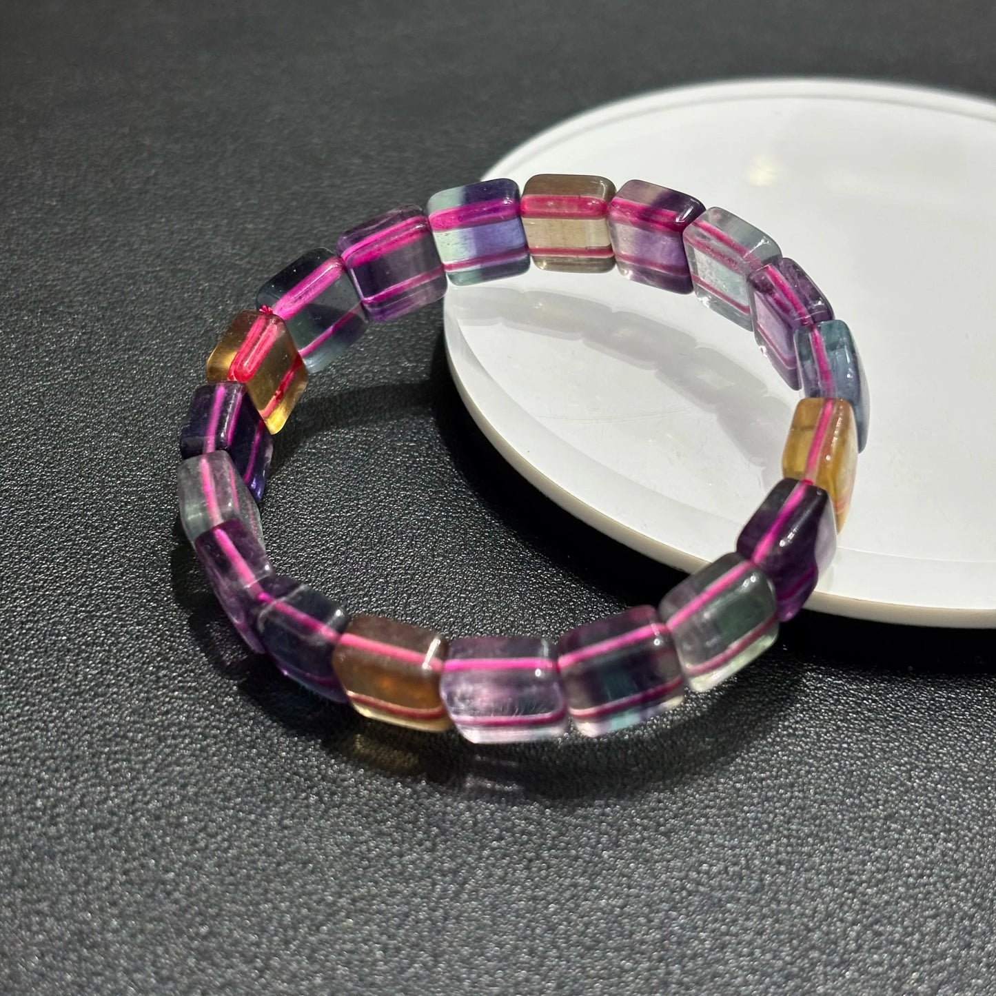 Close-up of a Natural Rainbow Fluorite Bracelet on a white plate, highlighting the 11mm square beads and color variations.