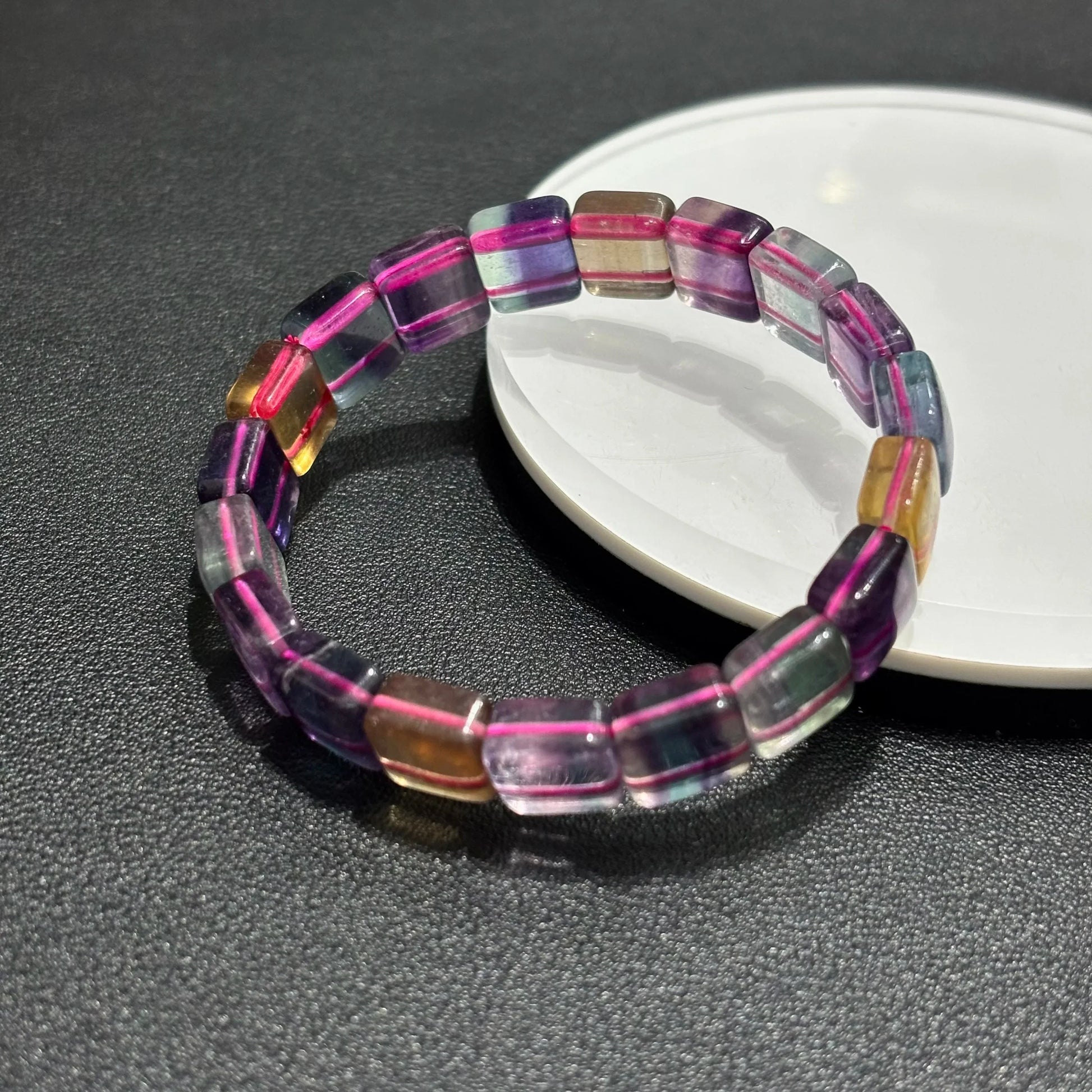 Close-up of a Natural Rainbow Fluorite Bracelet on a white plate, highlighting the 11mm square beads and color variations.
