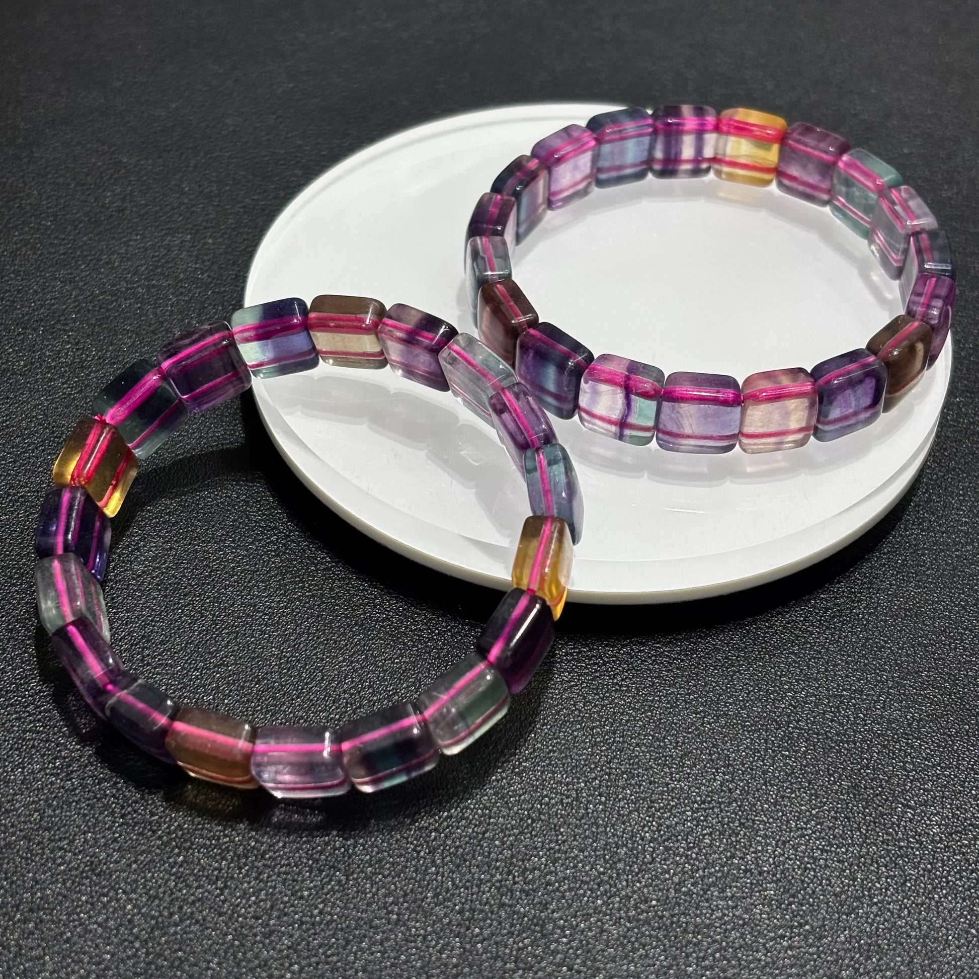 Two Natural Rainbow Fluorite Bracelets arranged on a white plate, emphasizing the vibrant purple, green, and yellow hues.