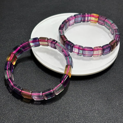 Two Natural Rainbow Fluorite Bracelets arranged on a white plate, emphasizing the vibrant purple, green, and yellow hues.