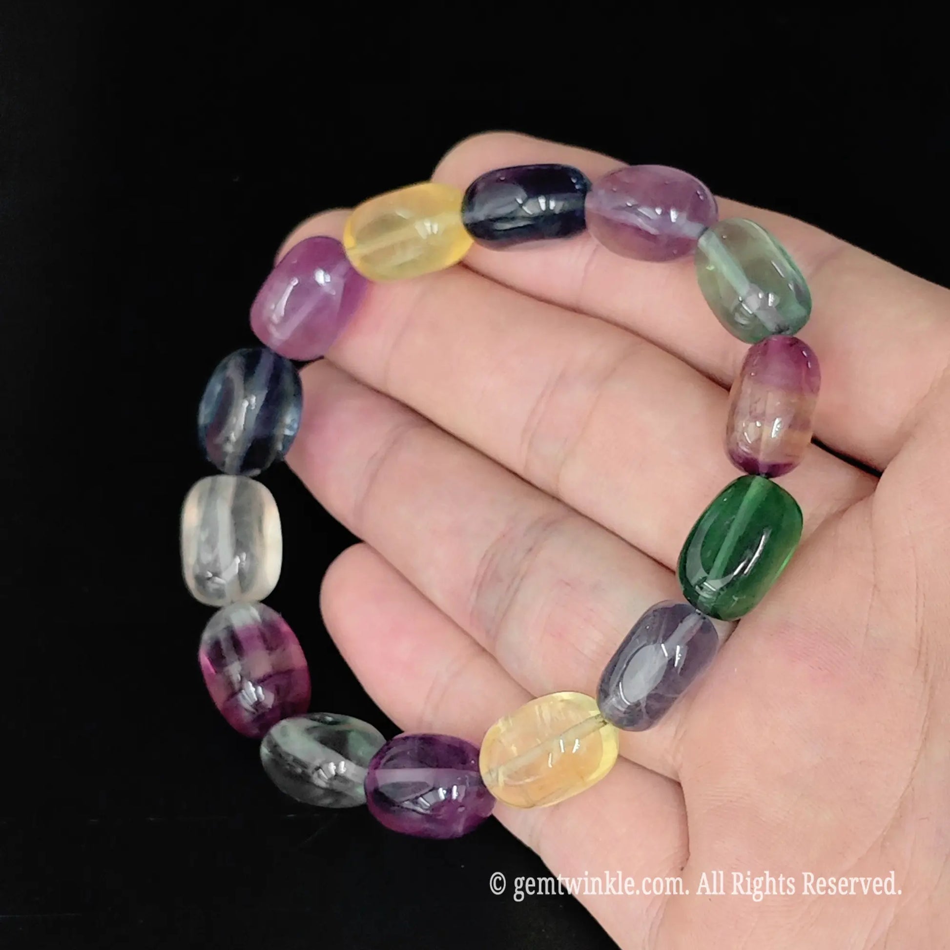 multi-color rainbow fluorite drum bead stretch bracelet displayed in open hand
