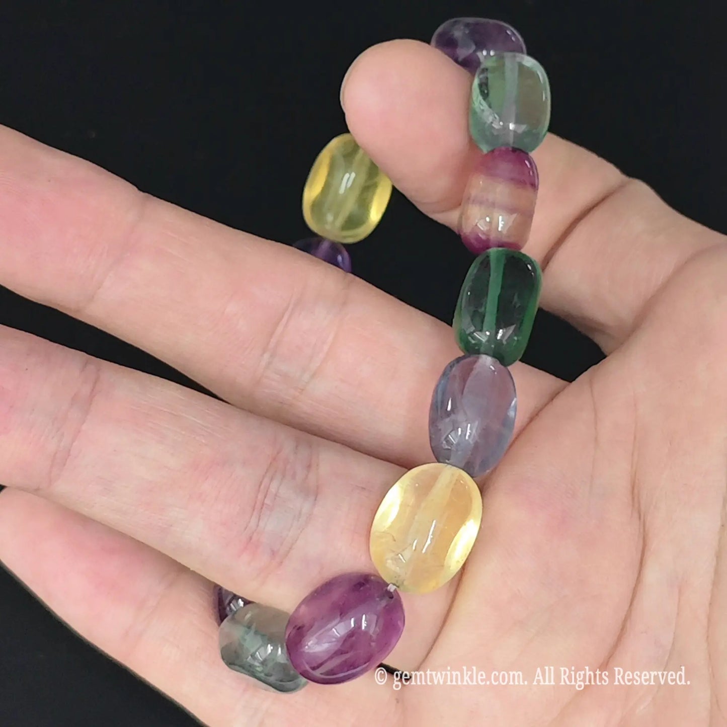 purple and green rainbow fluorite candy bead strand on fingers
