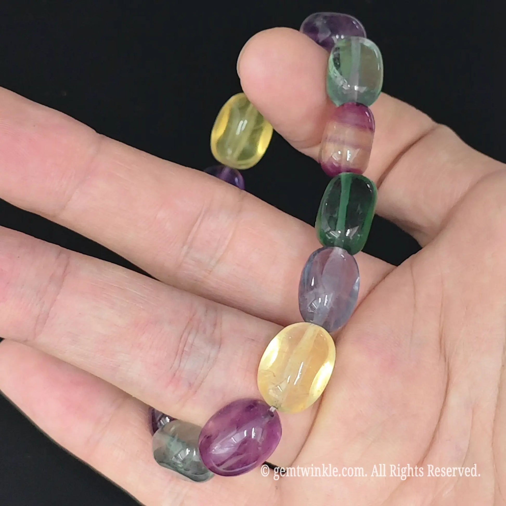 purple and green rainbow fluorite candy bead strand on fingers