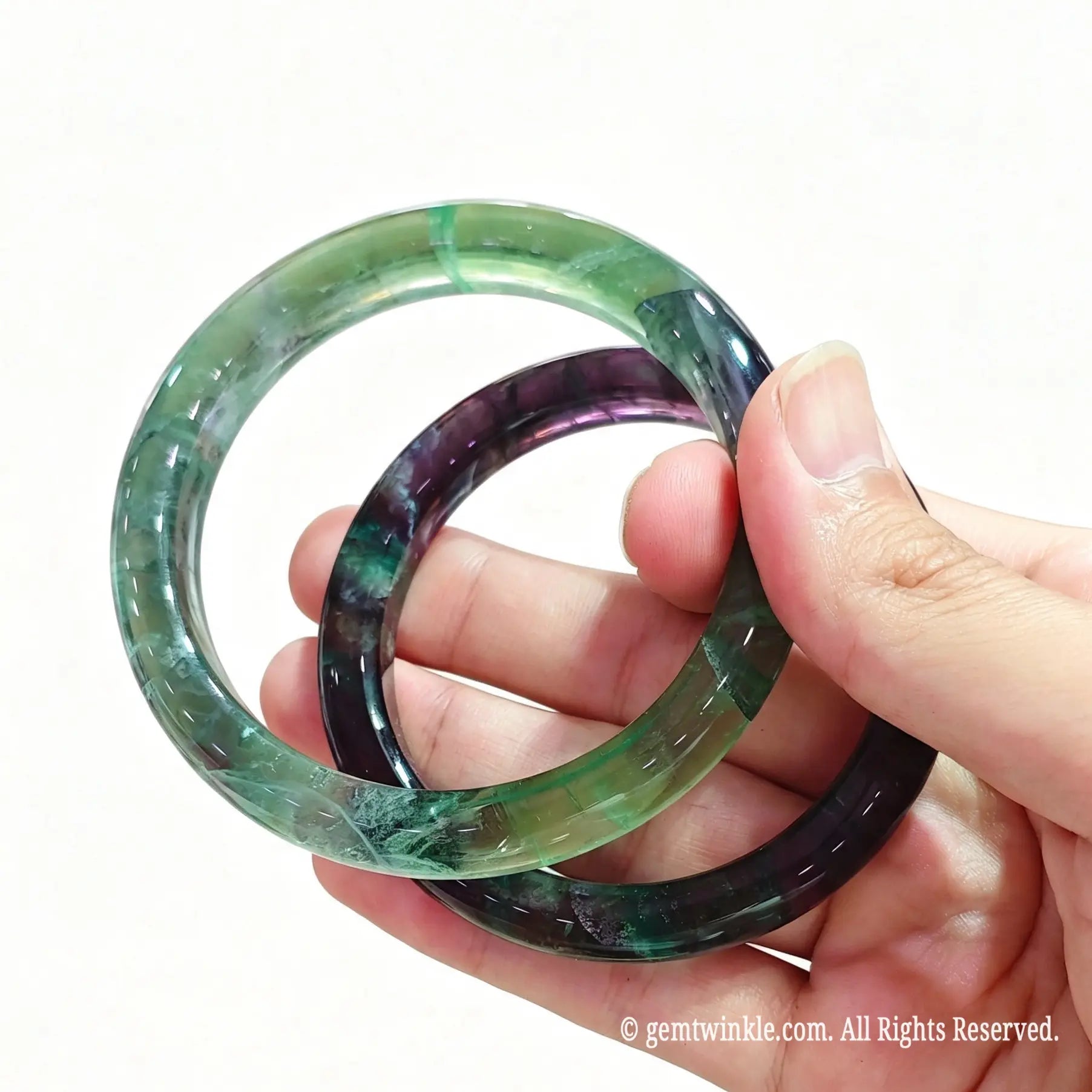Pair of rainbow fluorite crystal wristbands held in hand showing custom inner diameter sizing