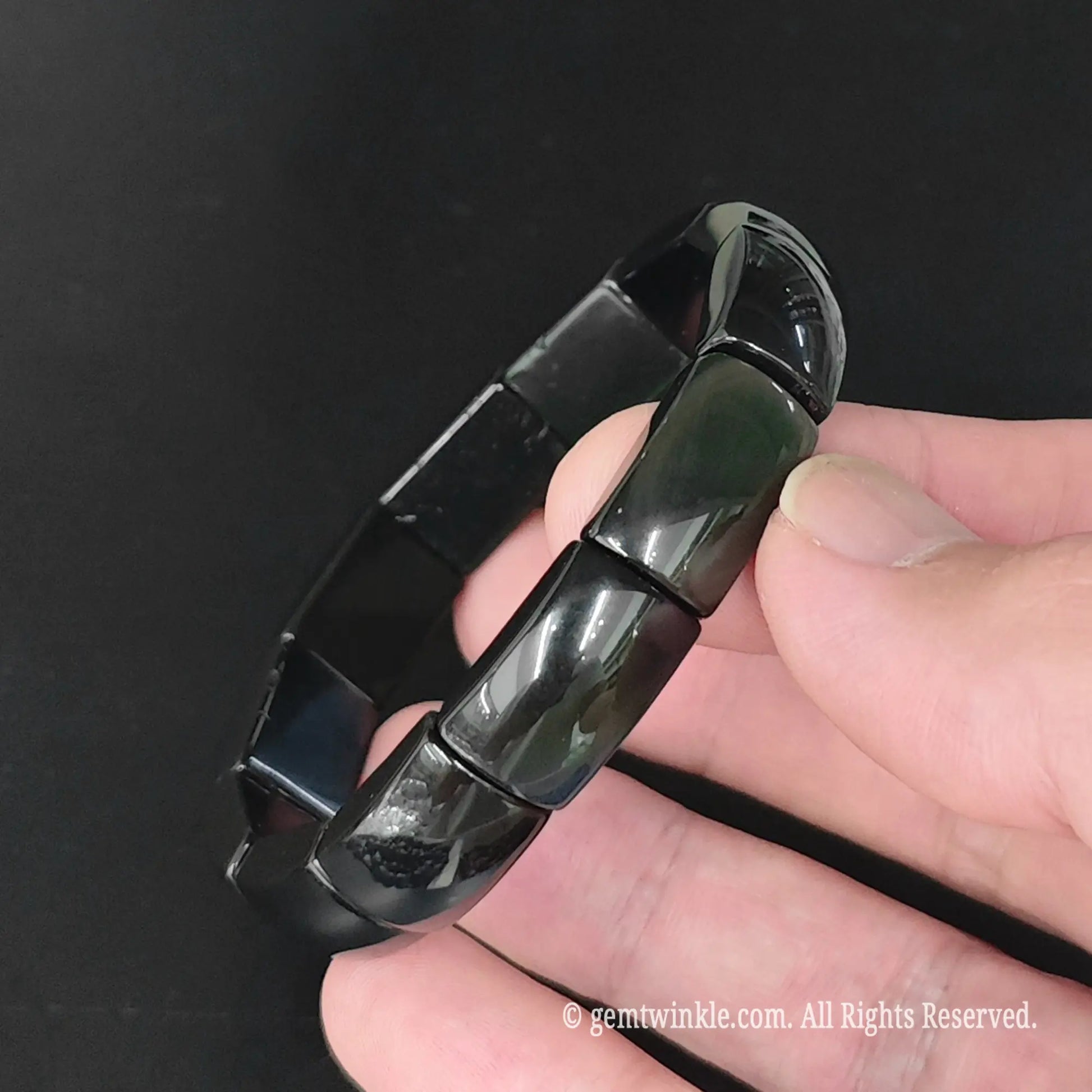 Side view of rainbow obsidian geometric plate cuff bracelet showing polished curved bead contours and glossy finish