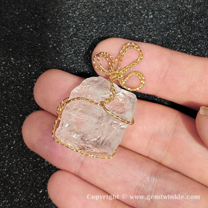 Handheld perspective of 3cm semi-translucent rock quartz rough wire wrapped pendant