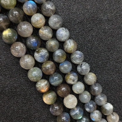 Close up macro of raw grade natural grey moonstone round beads showing blue light flash and rich mineral inclusions