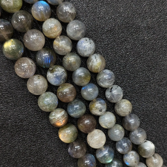 Close up macro of raw grade natural grey moonstone round beads showing blue light flash and rich mineral inclusions