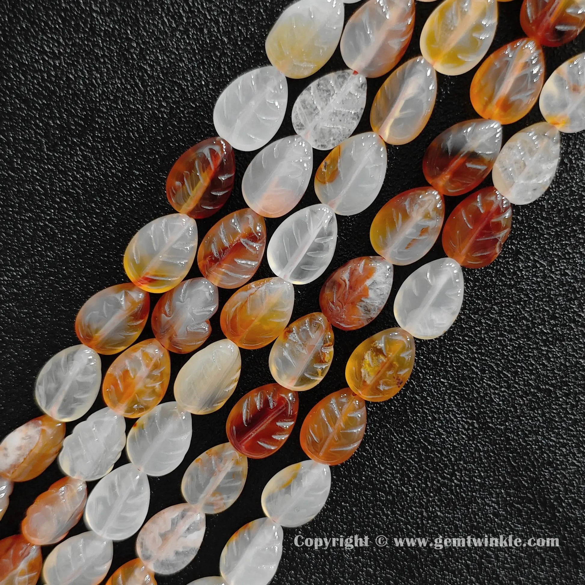 Angled view of color-treated red agate leaf carved gemstone strands laid together