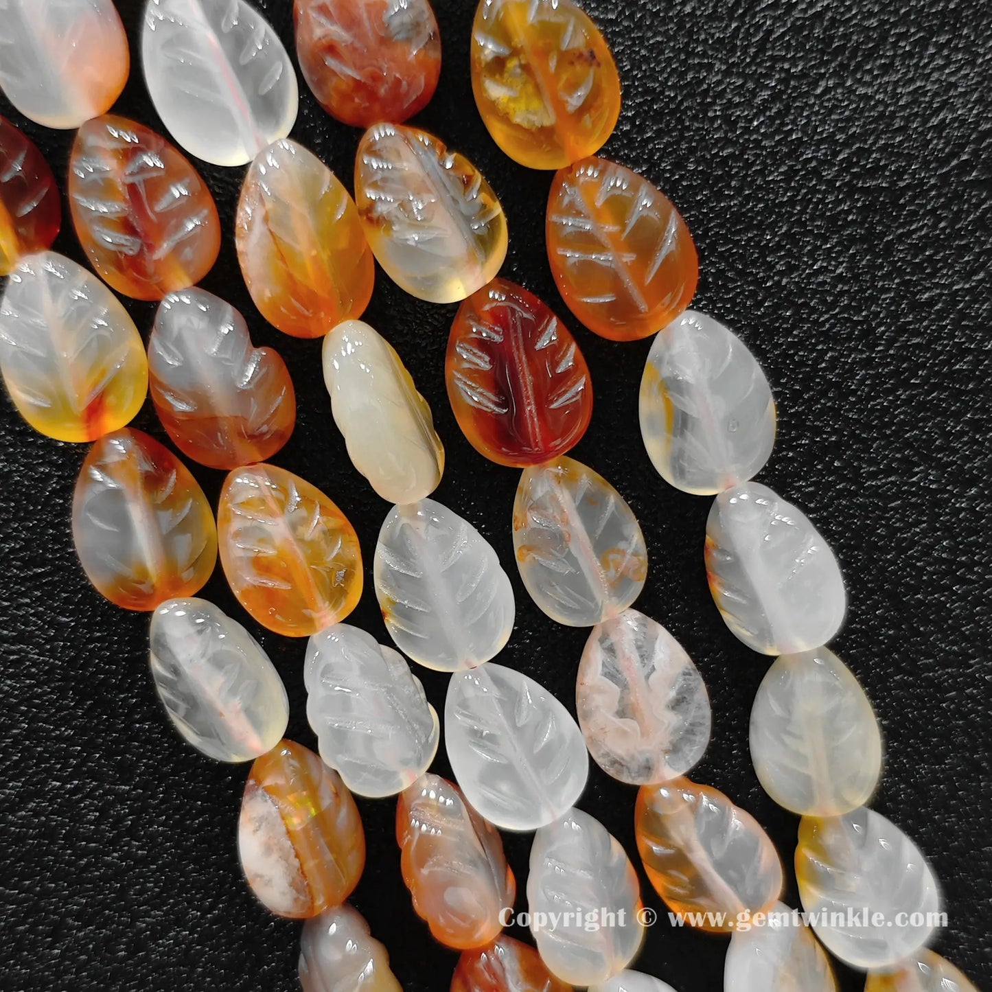 Color-dyed red agate leaf carved bead strand held over hand showing size scale