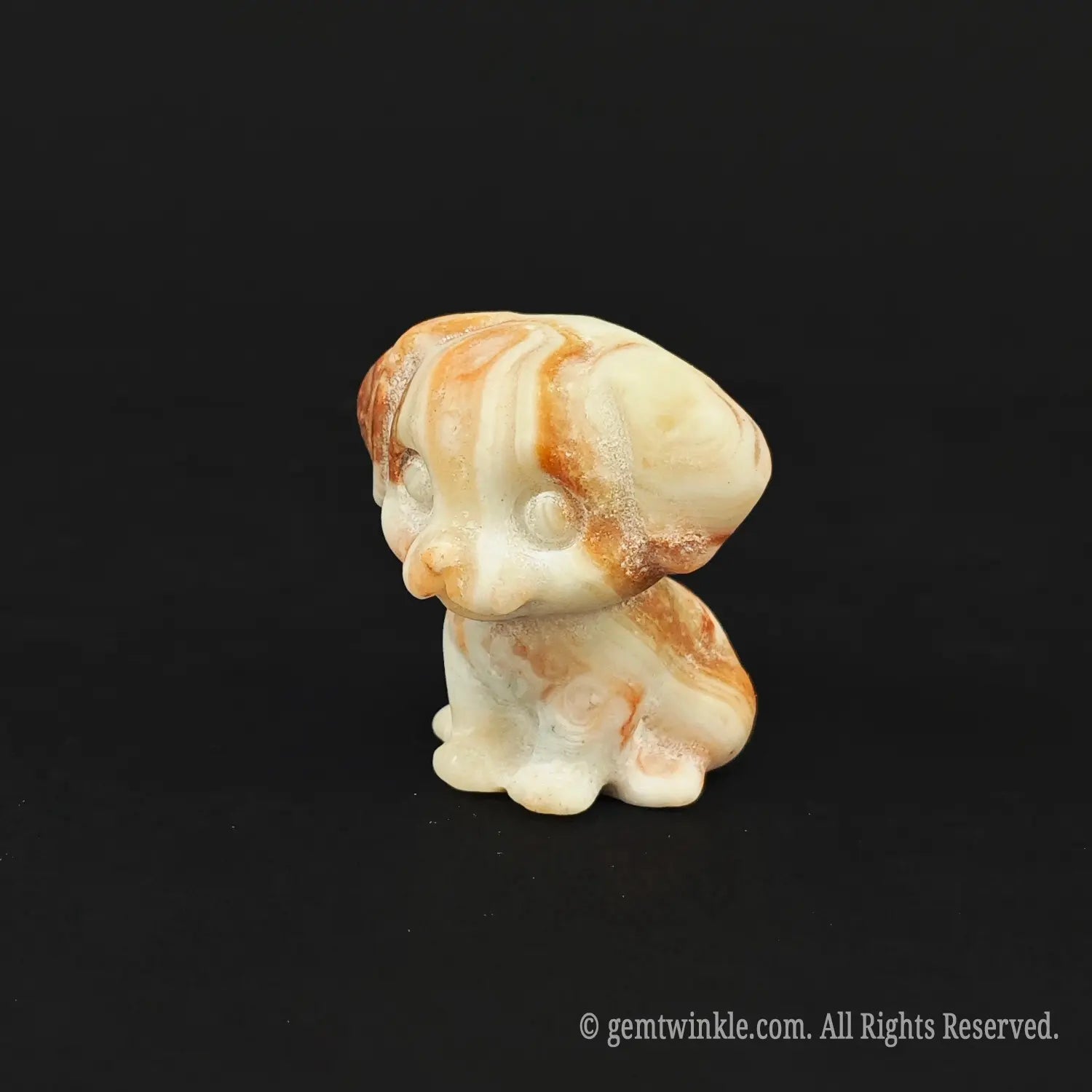 Side profile view of a red banded stone hound dog carving standing independently on a black background