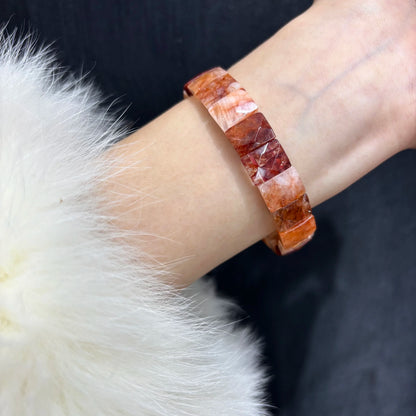  A person wearing a red hematoid fire quartz bangle bracelet on their wrist, showcasing the fit and style.