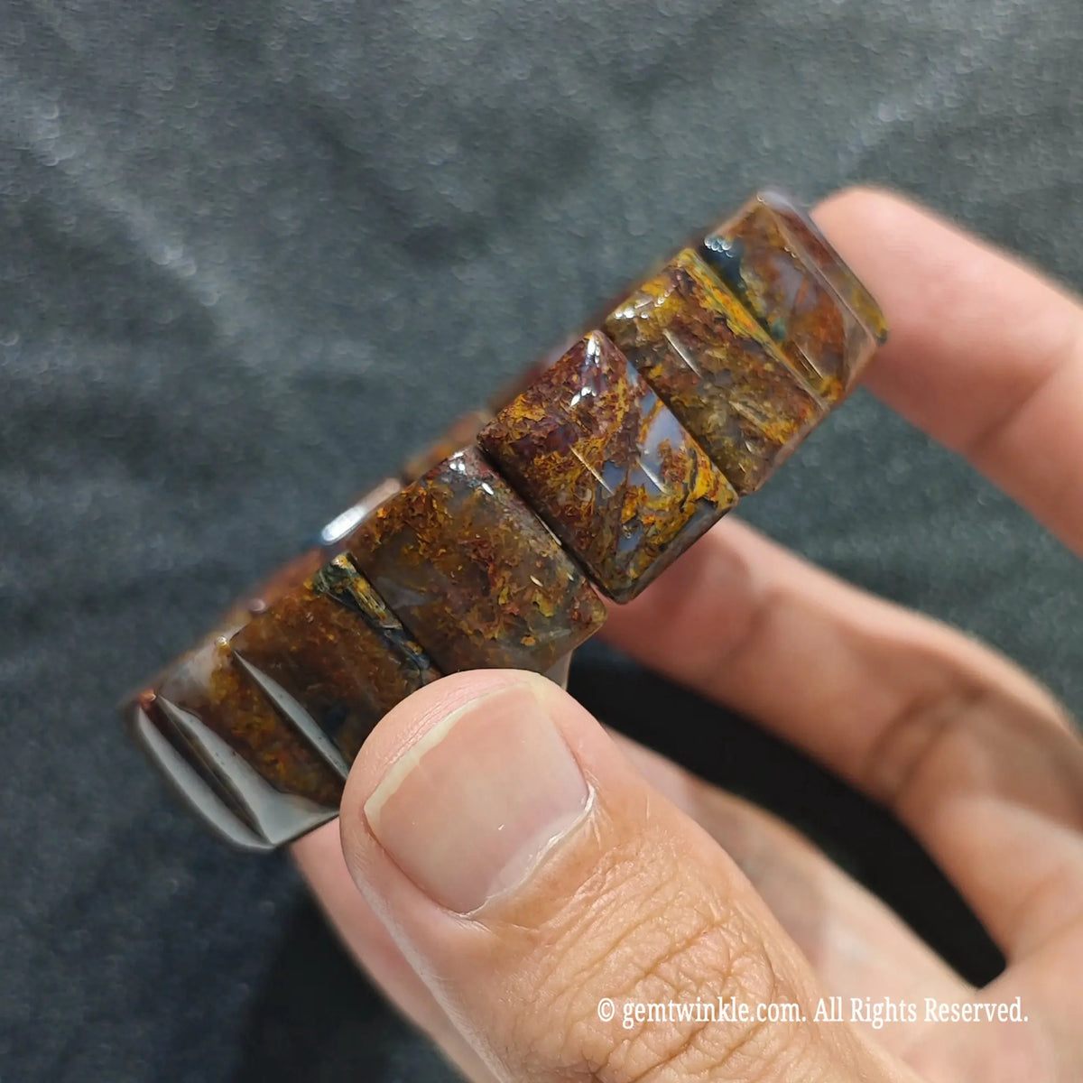Close up view of red pietersite geometric wristband showing smooth polish and rich mineral fibers