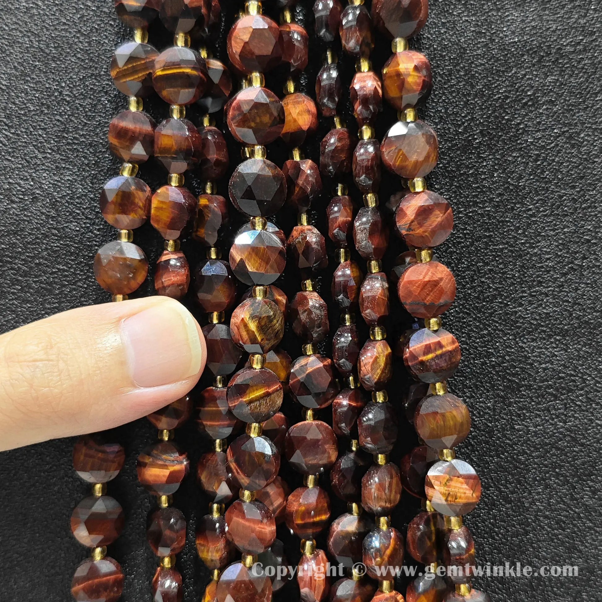 Hand holding strands of red tiger eye hexagram flat disc beads in 8mm and 10mm