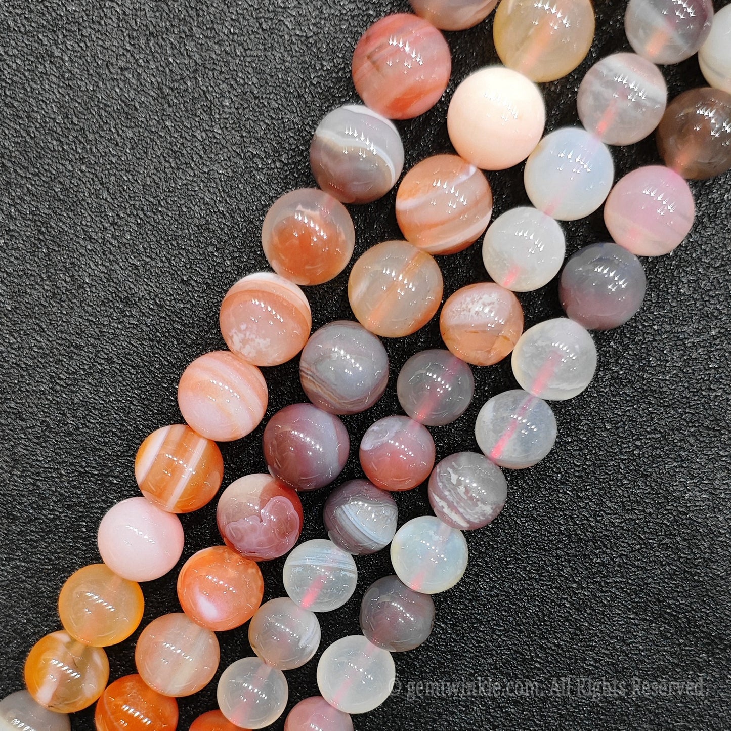 Close up view of red banded agate round loose gemstone beads showing unique concentric parallel stripes and high polished finish