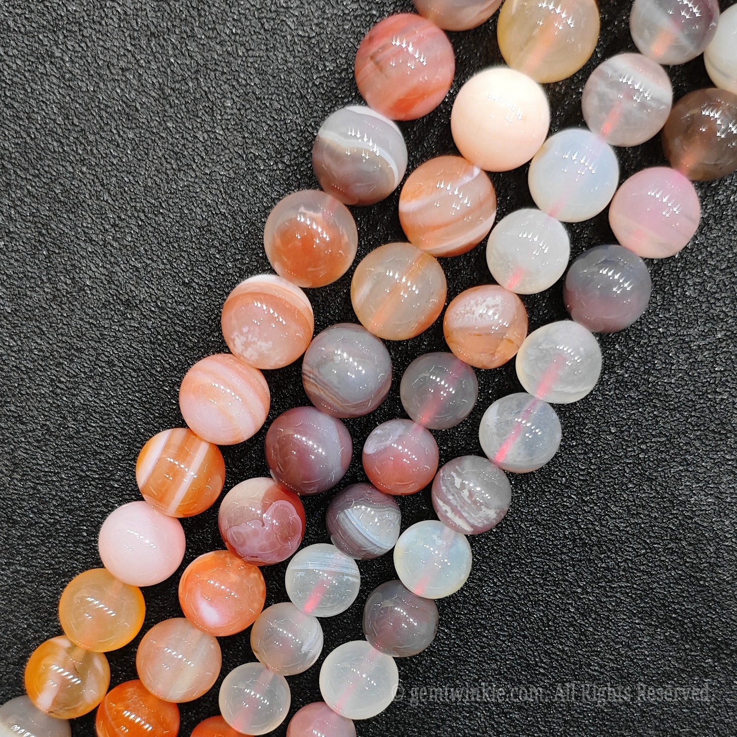 Close up view of red banded agate round loose gemstone beads showing unique concentric parallel stripes and high polished finish