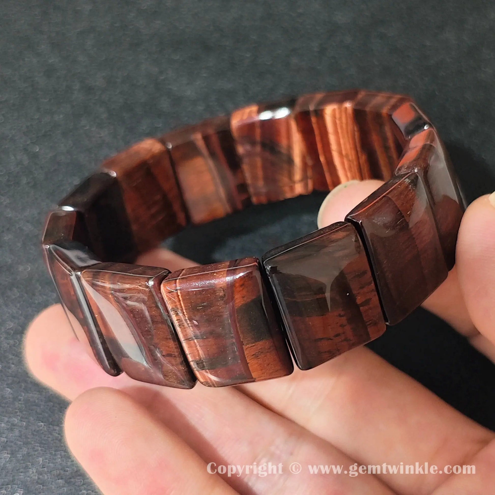 close up of red tigers eye plate bracelet showing durable elastic cord construction and uniform fit