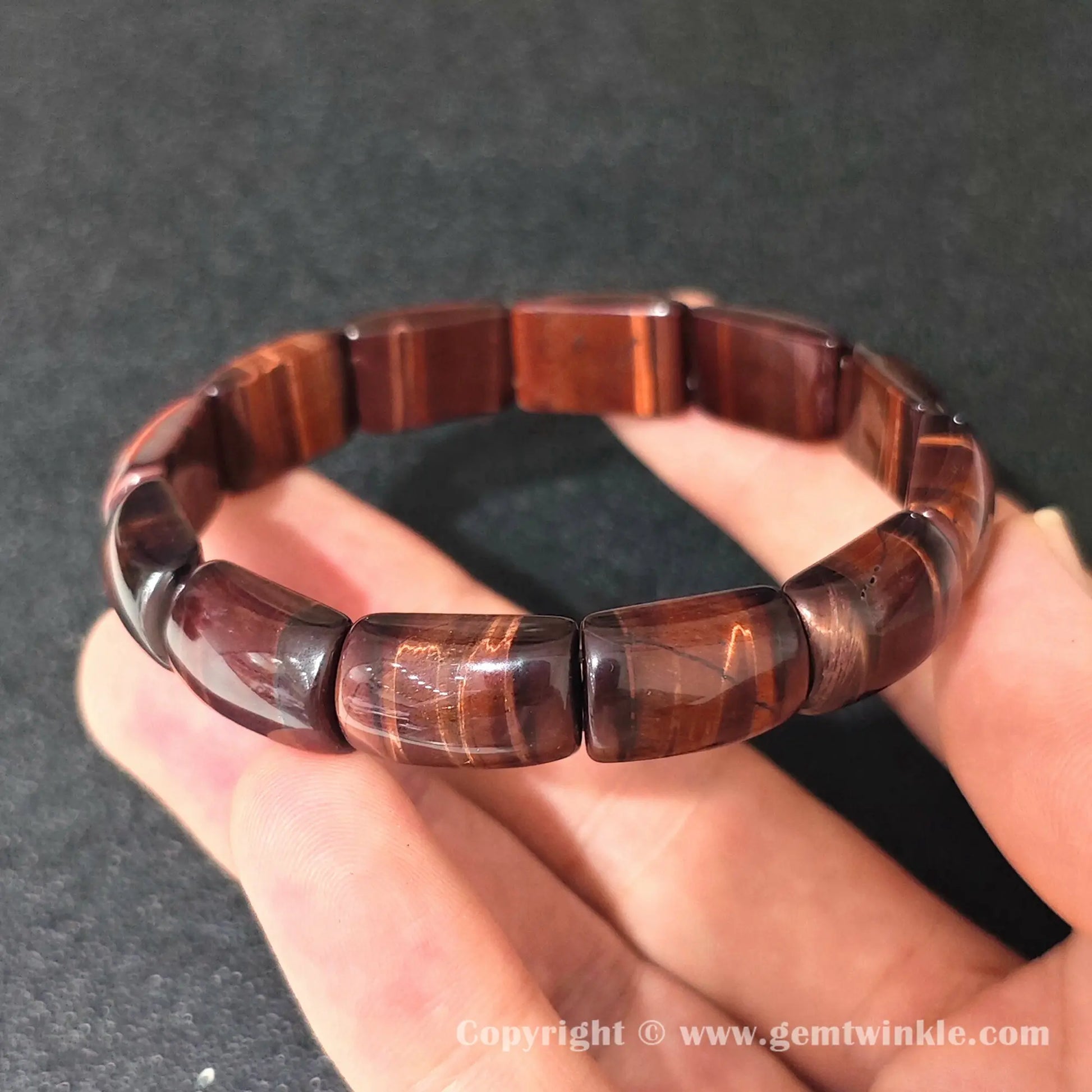 red tigers eye curved plate stretch bracelet displayed over open palm highlighting glossy finish