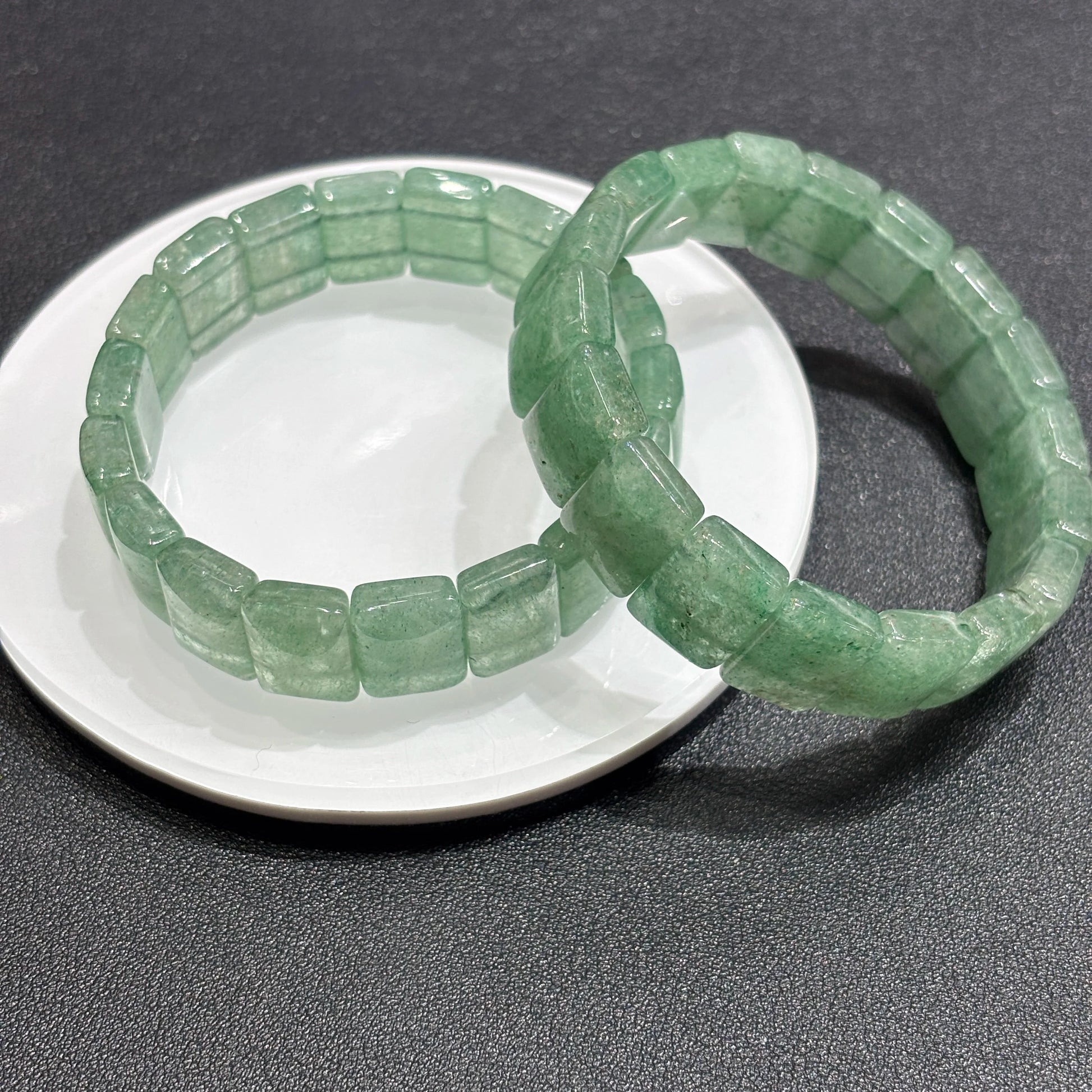 Overhead view: natural green strawberry quartz square bead bracelet; consistent width, no metal, elastic cord hidden for seamless elegance