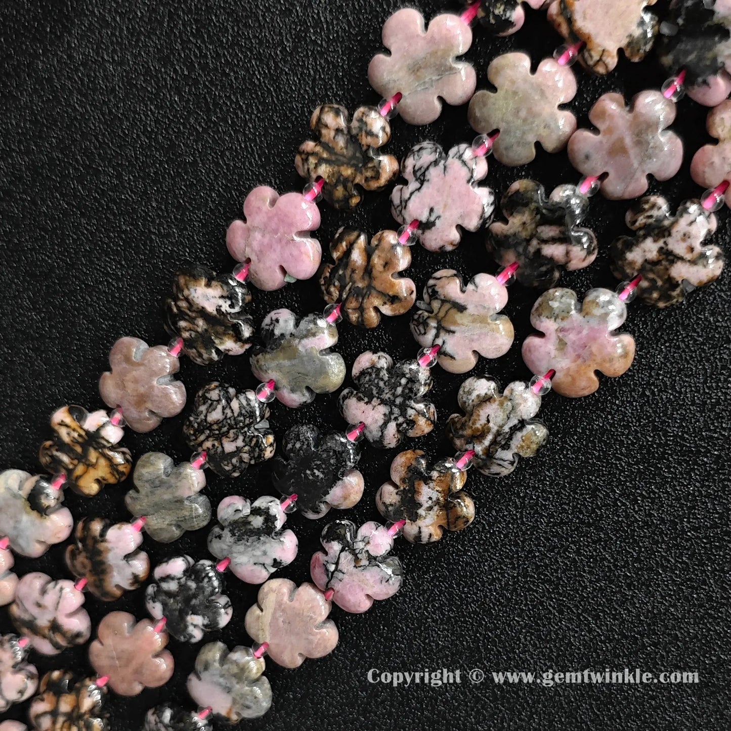 Angled view of natural pink rhodonite floral carved gemstone strands