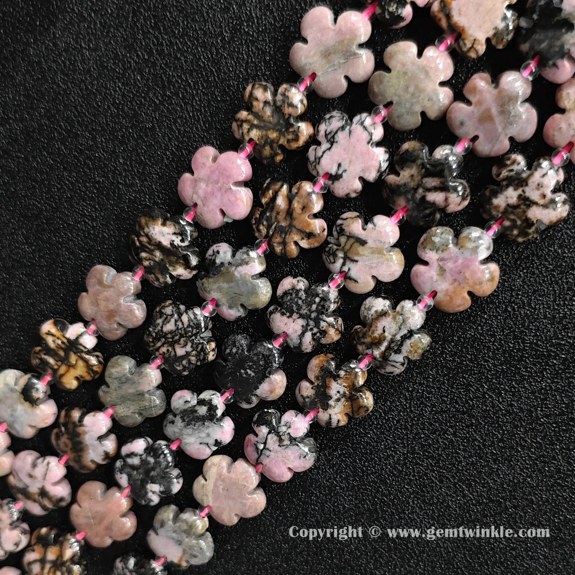 Angled view of natural pink rhodonite floral carved gemstone strands