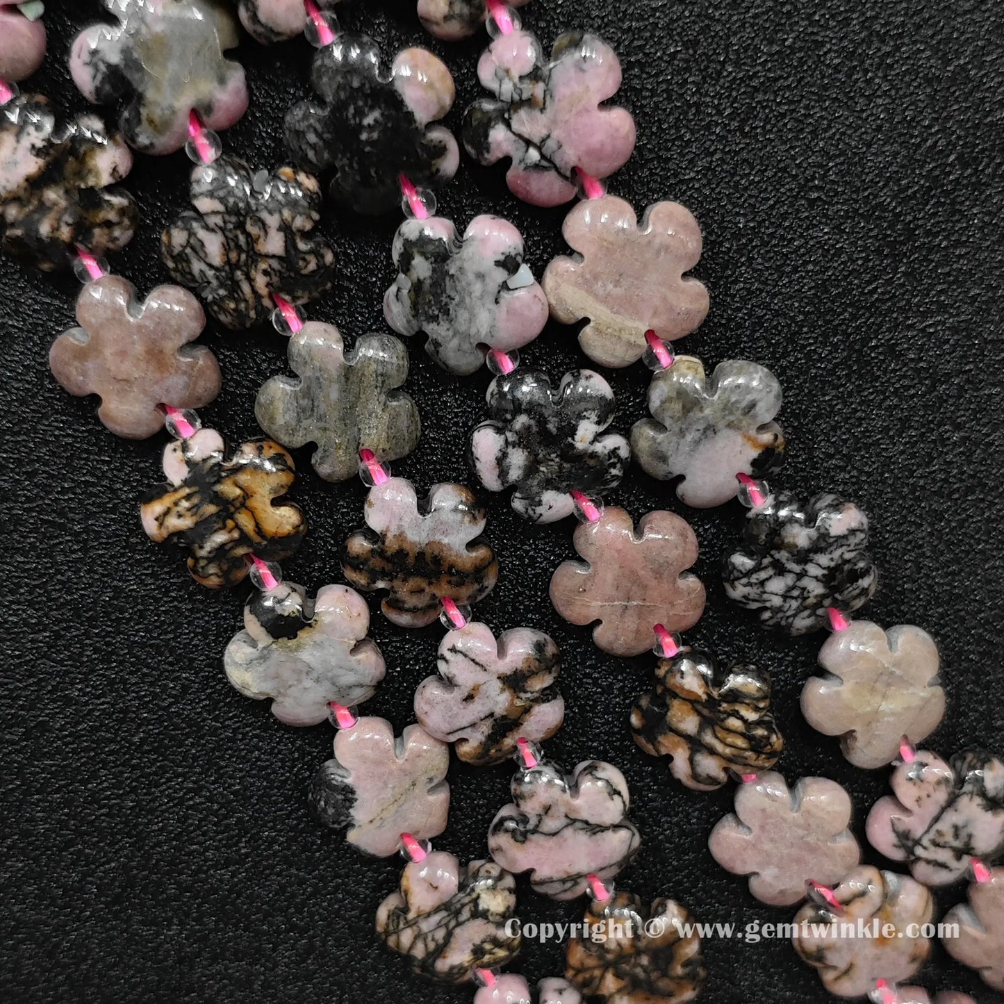 Natural rhodonite plum blossom carved bead strand held over hand showing size scale