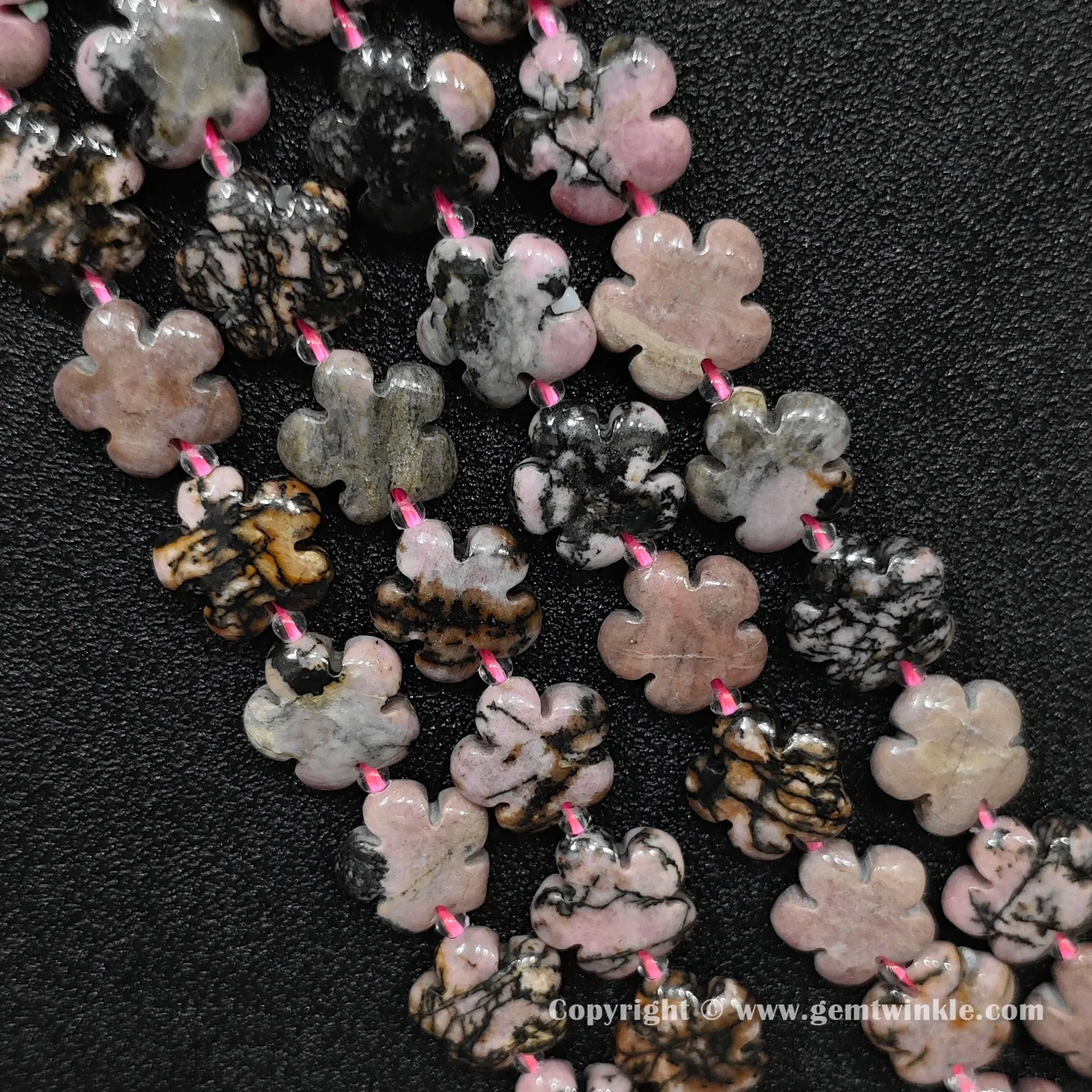 Natural rhodonite plum blossom carved bead strand held over hand showing size scale