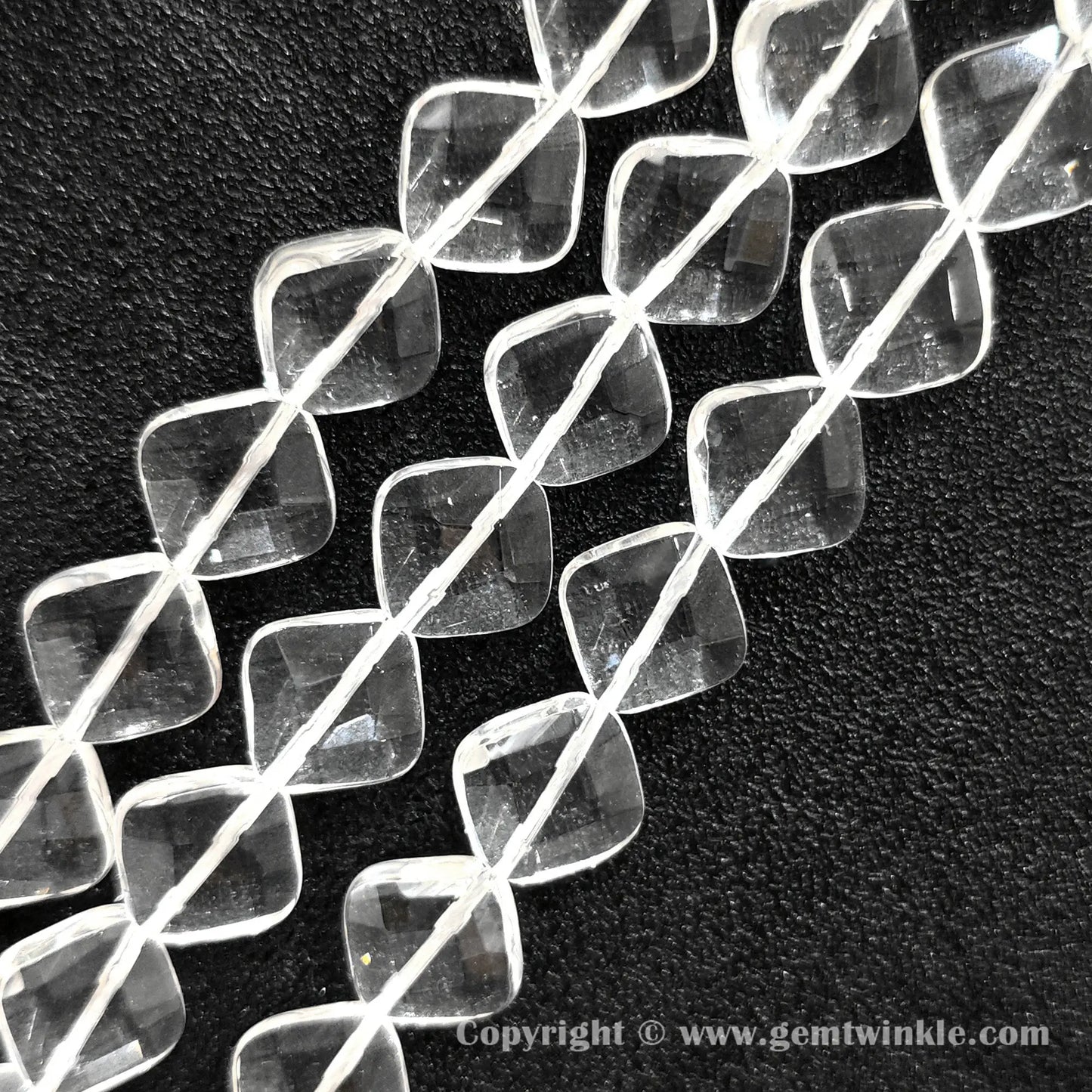 Close up view of faceted rhombus slice clear quartz beads showing light reflections