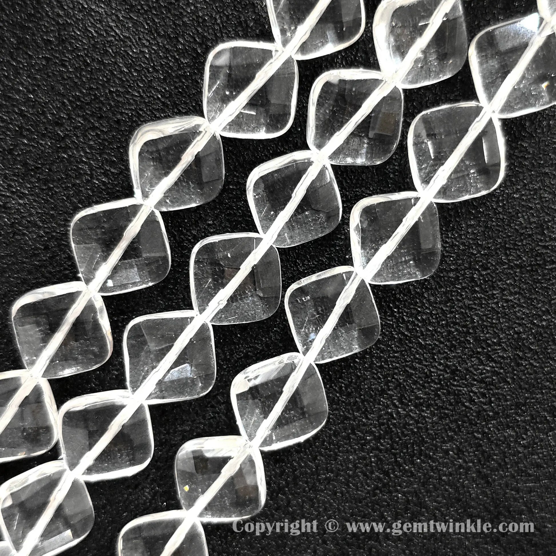 Close up view of faceted rhombus slice clear quartz beads showing light reflections
