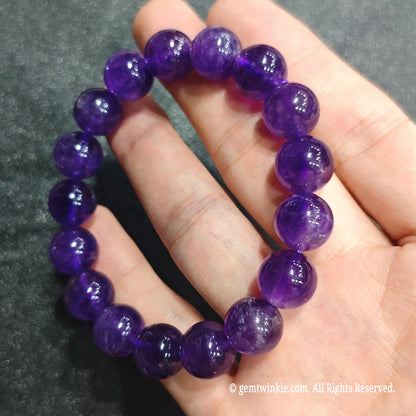 Full circle view of a rich violet quartz stretch wristlet resting on palm showcasing royal purple color saturation