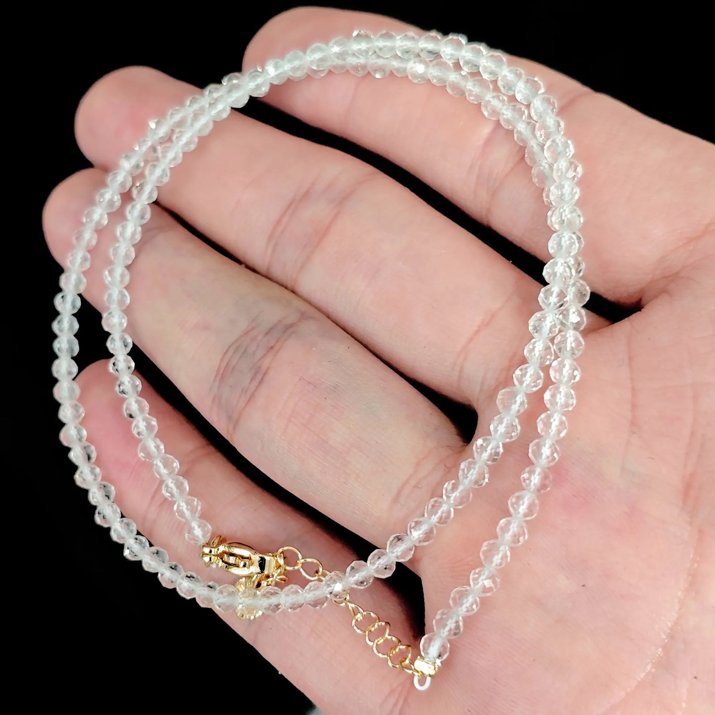 faceted clear quartz micro bead necklace loop with gold tone extender chain in hand