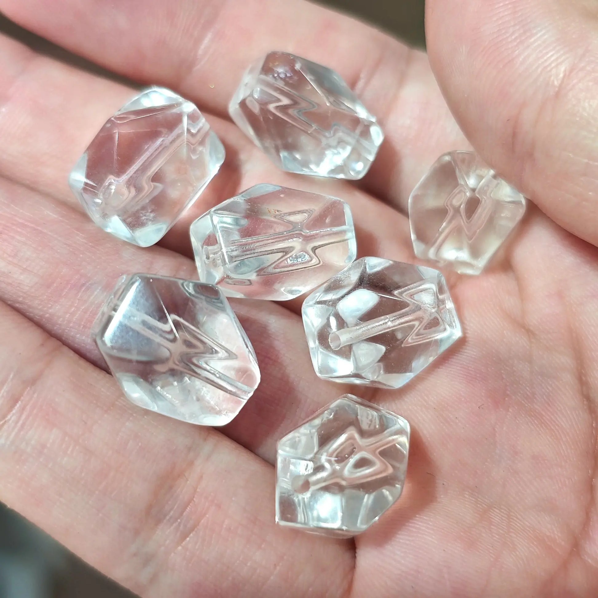 Close up view of natural rock crystal freeform beads in hand showcasing subtle wispy inclusions