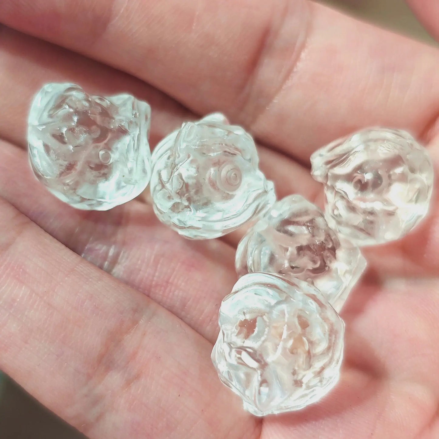 Close up view of natural rock crystal lion head beads showing fine wispy inclusions and polished luster