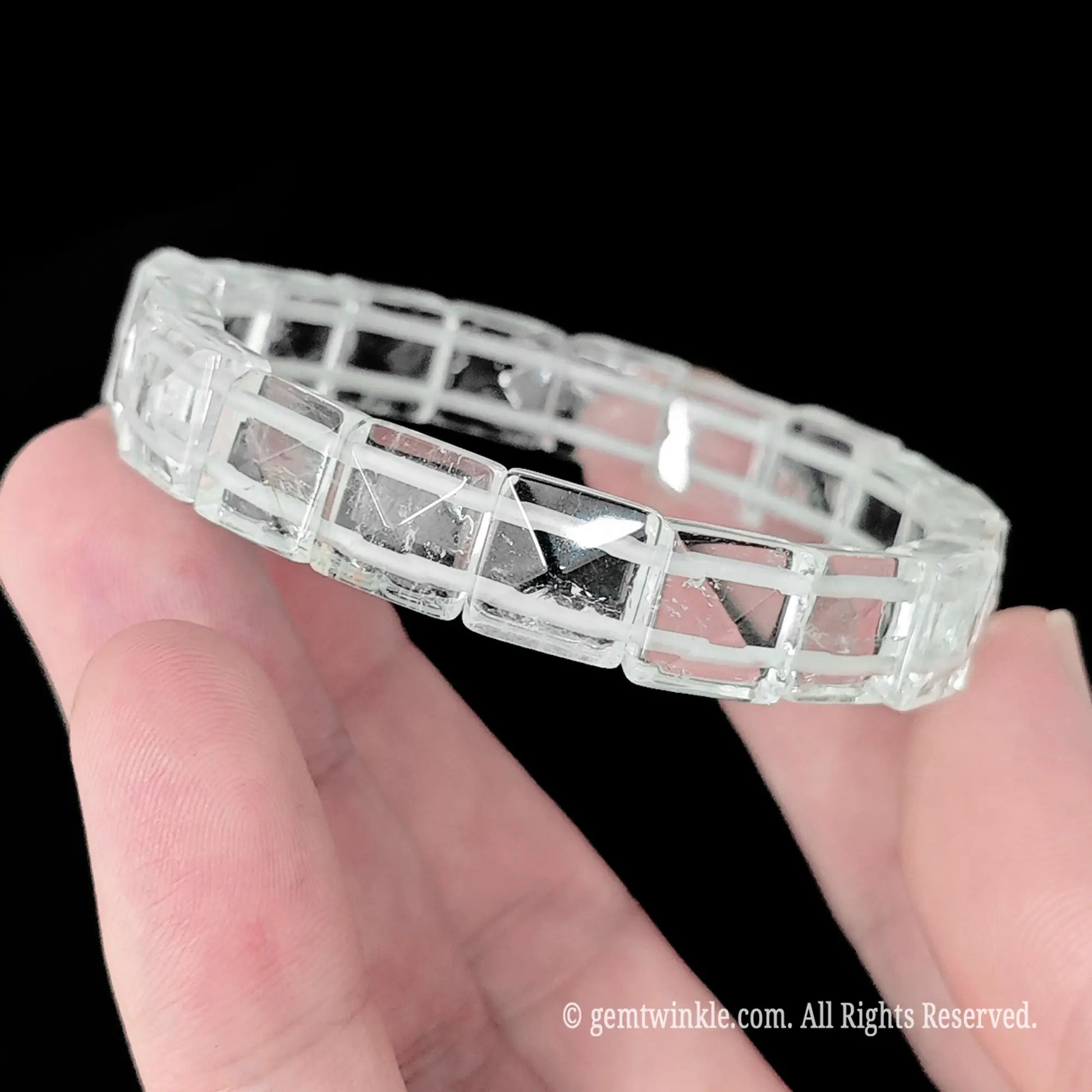 Rock crystal pyramid cut square bead stretch bracelet held showing clear transparent matrix and natural ice veils
